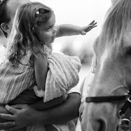 Sadie at three, reaching for a horse