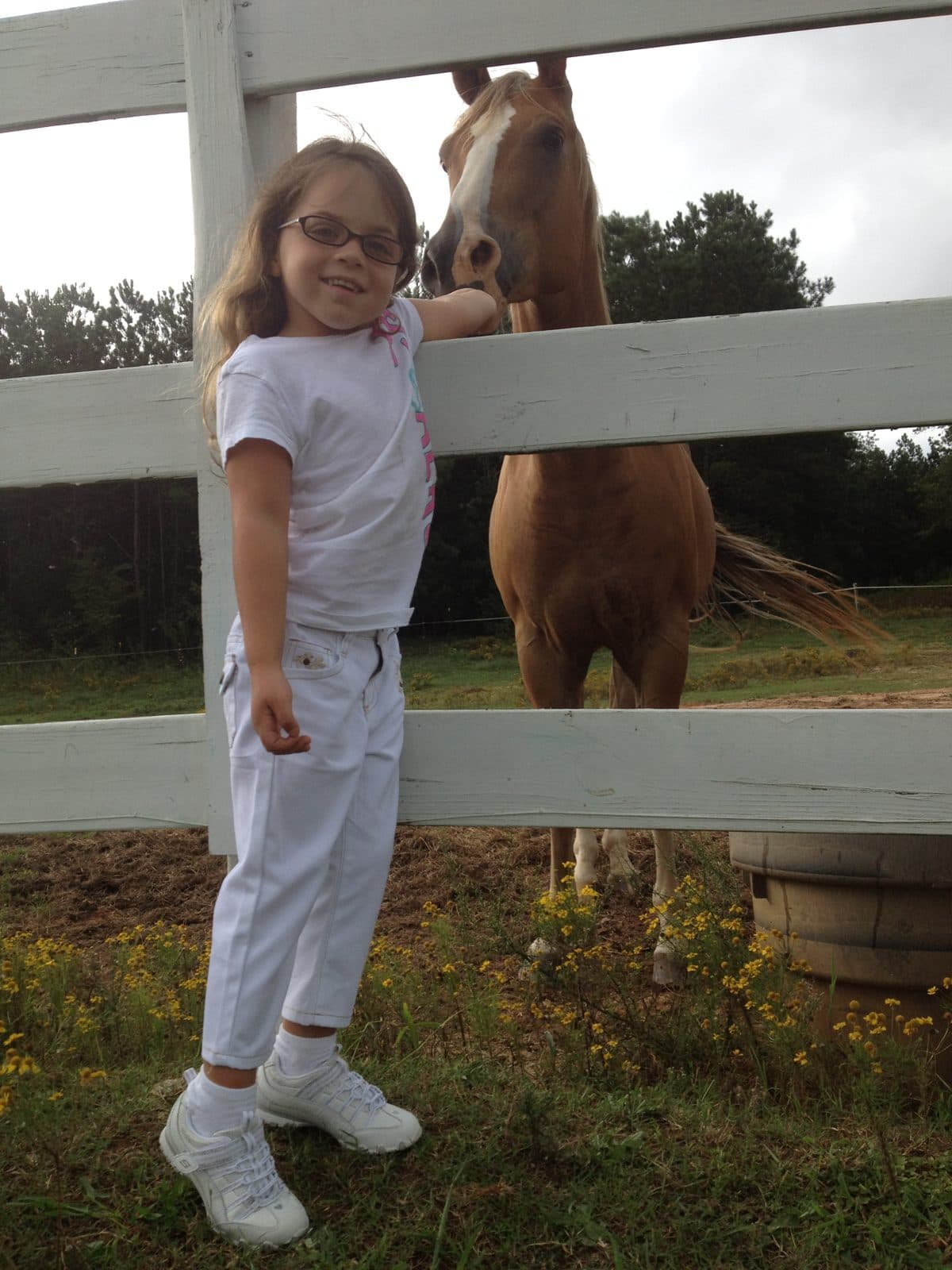 Sadie as a girl beside a palomino at the farm fence